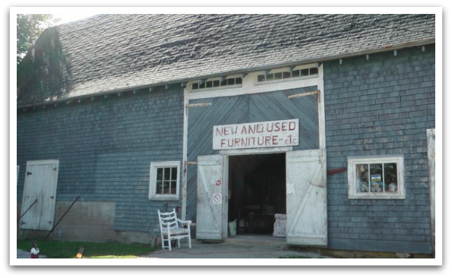 Countway’s Furniture Barn exterior - a grey/blue barn with a hand-painted sign above the white barn doors reading "new and used furniture - etc."