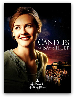 A movie poster with a bay and group of people at night in the background with Alicia Silverstone smiling into the distance on the front. White text reads "Candles on Bay Street Hallmark".
